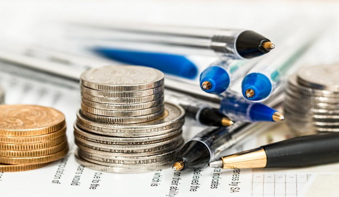 Geld welches zusammen mit Stiften auf Papier liegt