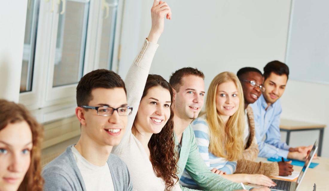 Gruppe von Personen bei einem Vortrag. Eine Frau meldet sich. (c) Robert Kneschke / AdobeStock
