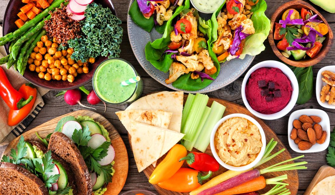 Ein Tisch voll mit veganen und vegetarischen Lebensmitteln: Früchte, Brot, Obst, Salat