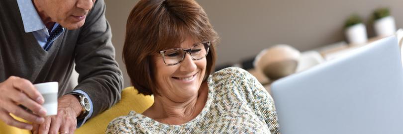 Paar mittleren Alters schaut zusammen in den Laptop auf der Couch.