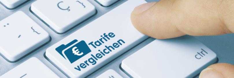 Jemand drückt auf einer Computertastatur auf eine Taste namens "Tarife vergleichen".
