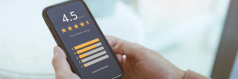 Jemand hält ein Handy in der Hand, auf dem eine Fünf-Sterne-Online-Bewertung zu sehen ist.