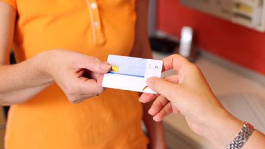 Patientin überreicht ihre Versichertenkarte von der Krankenkasse der Zahnarzthelferin in der Praxis.