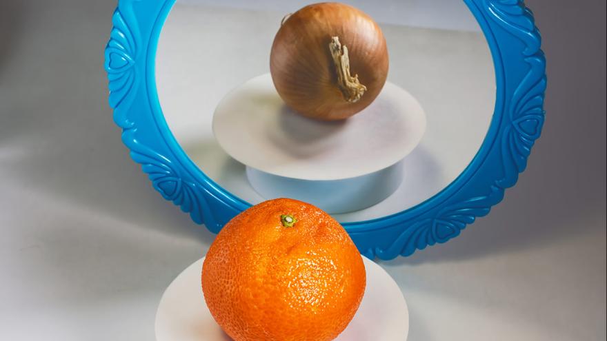 Täuschende Reflektion: vor dem Spiegel liegt Orange und im Spiegel sieht man eine Zwiebel