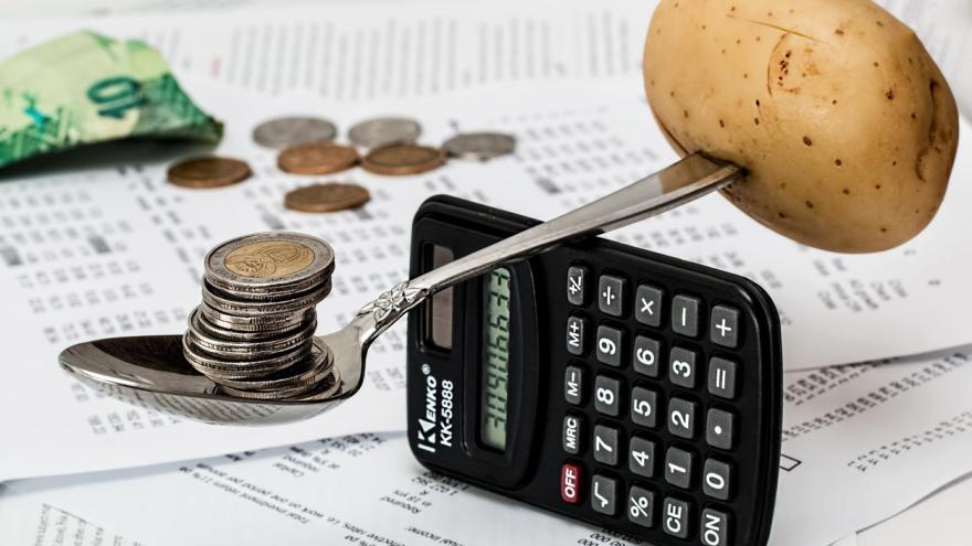 Ein Taschenrechner auf dem ein Löffel mit Münzen und einer Kartoffel balanciert (c) stevepb / Pixabay