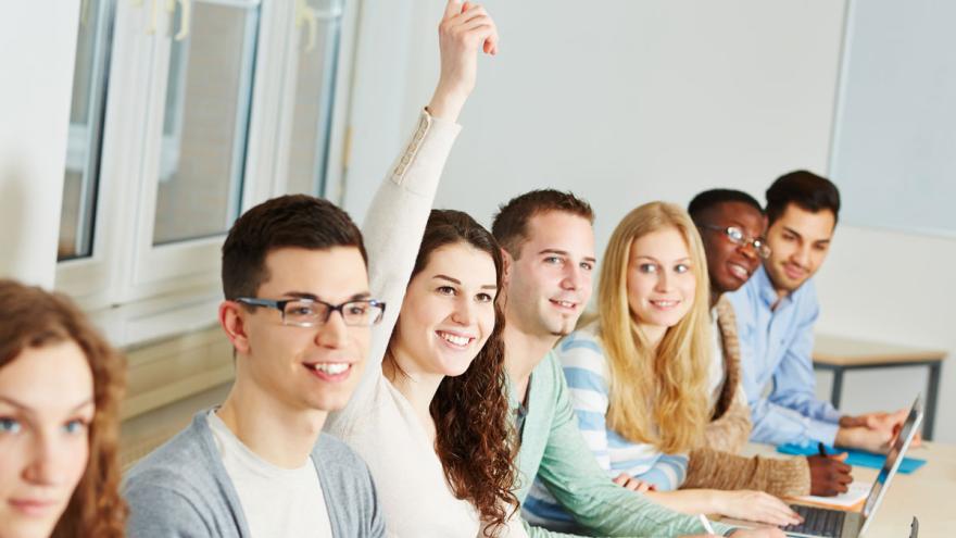 Gruppe von Personen bei einem Vortrag. Eine Frau meldet sich. (c) Robert Kneschke / AdobeStock