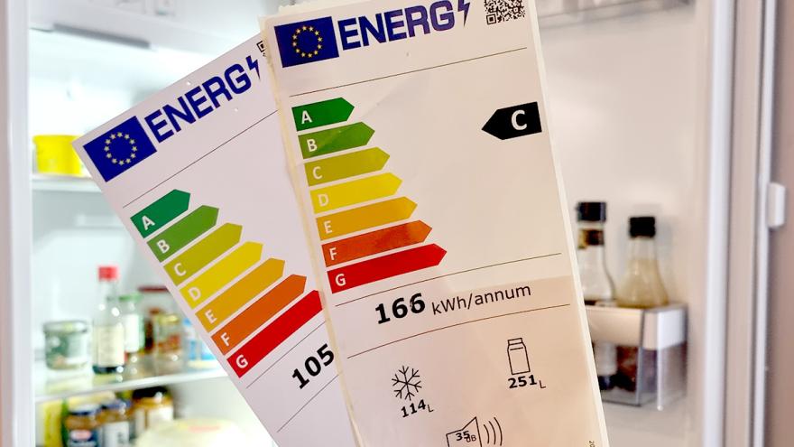 Zwei Energielabel vor einem offenen Kühlschrank