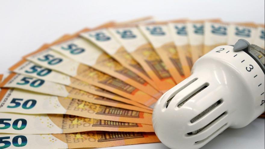 50-Euro-Scheine liegen gefächert um ein Heizungsthermostat