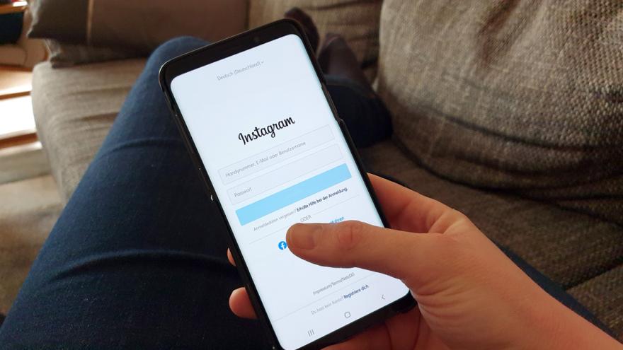 Foto aus der Perspektive einer Person, die auf einer Couch liegt und ein Smartphone in der Hand hält, das die Login-Seite von Instagram zeigt