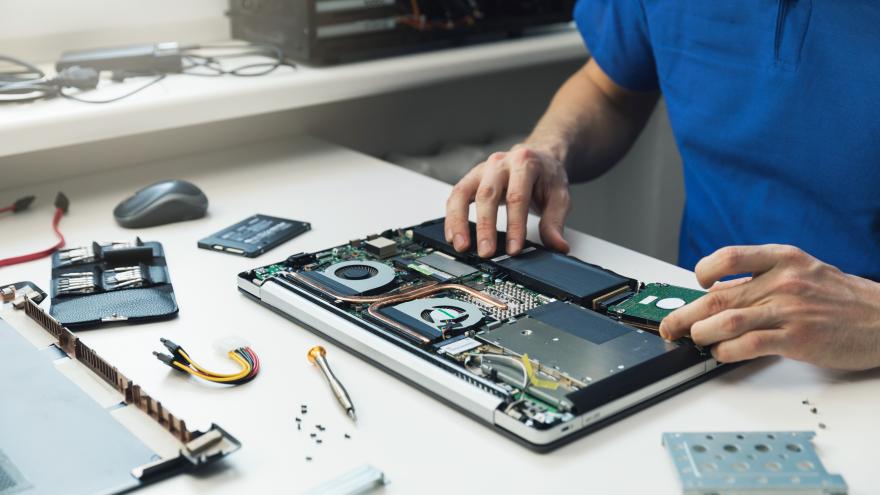 Ein Mann versucht, einen kaputten Laptop zu reparieren.