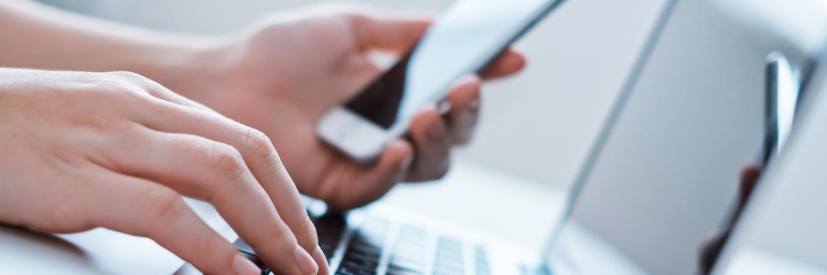 Nahaufnahme von jemandem, der Laptop und Smartphone nutzt