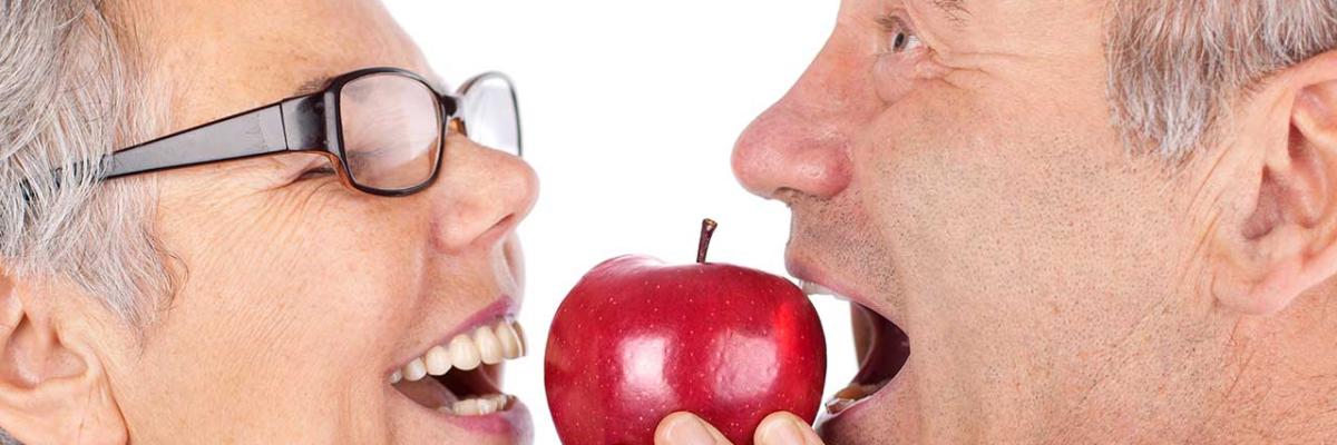Freudiges Paar beißt in roten Apfel 