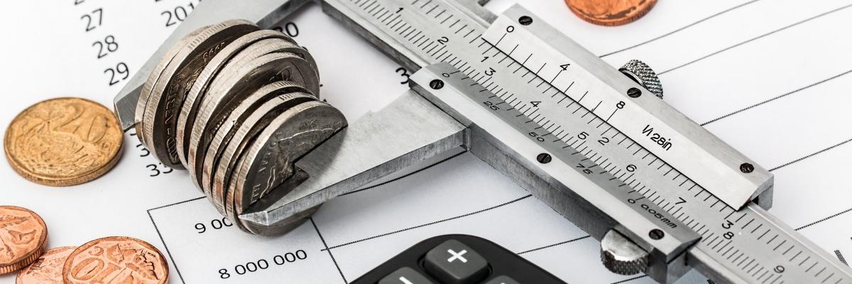Euromünzen und ein Taschenrechner liegen auf einem Dokument mit Zahlenreihen