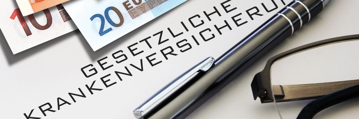 Geldscheine und ein Stift liegen auf einem Dokument zur gesetzlichen Krankenversicherung