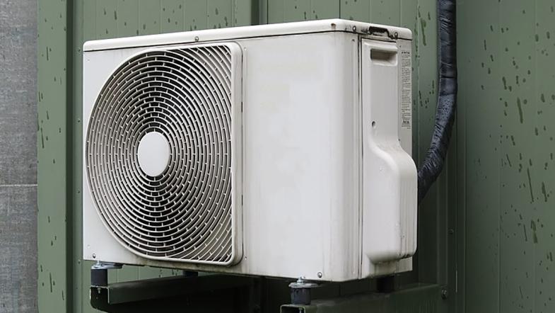 Ein Klimagerät hängt an der Außenwand eines Gebäudes.