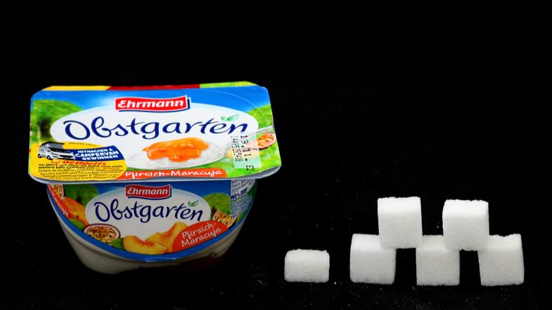 Joghurtbecher von Ehrmann Obstgarten und daneben eine Zuckerwürfel-Pyramide