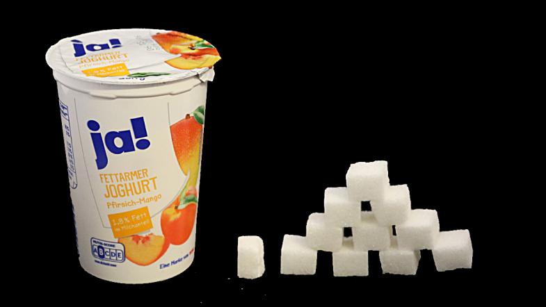 Joghurtbecher von ja! und daneben eine Zuckerwürfel-Pyramide