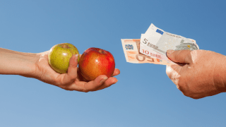 Die Nahaufnahme zeigt zwei Hände. Eine davon hält zwei Äpfel, die andere einige Euro-Geldscheine.