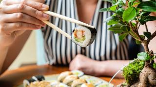 Eine Person isst Sushi mit Stäbchen