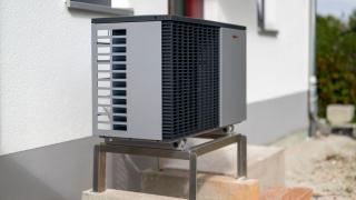 Eine Wärmepumpe, die vor einem offensichtlichen Einfamilienhaus steht