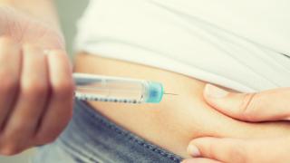 Jemand setzt sich eine Spritze an den Bauch